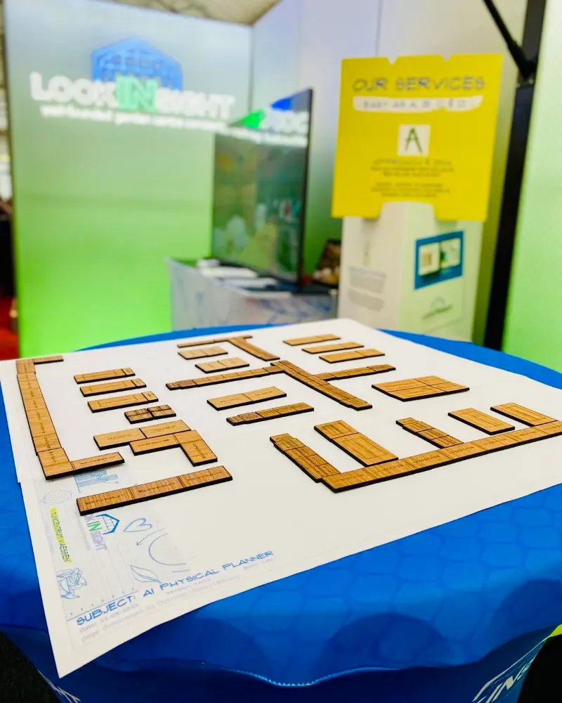 The A1 plan sheet on a blue table at a trade fair stand, covered in wooden fixture tiles arranged into a store layout.