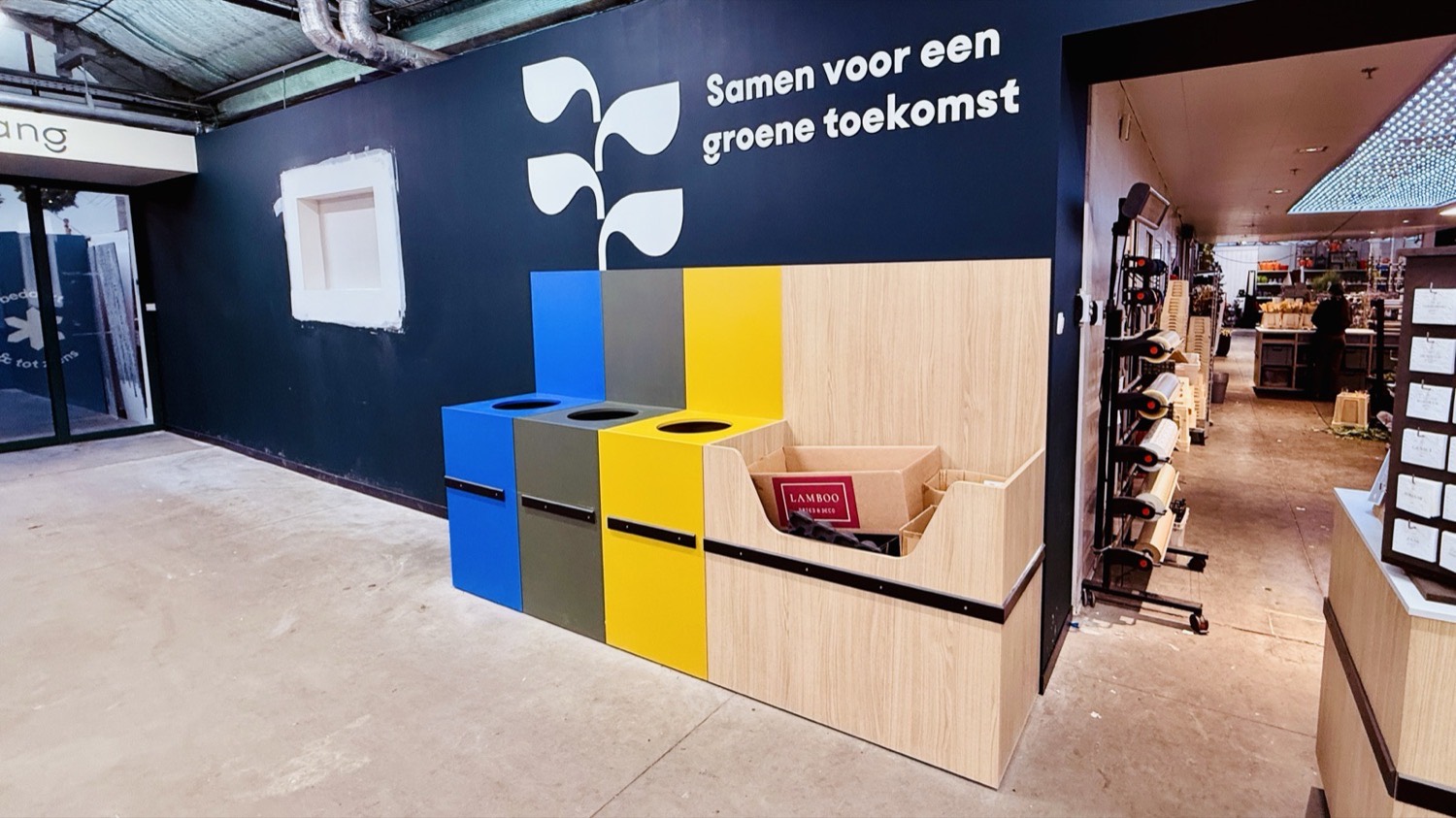 Eurotuin Merelbeke: recycling station in brand colours under the wall text 'Samen voor een groene toekomst'